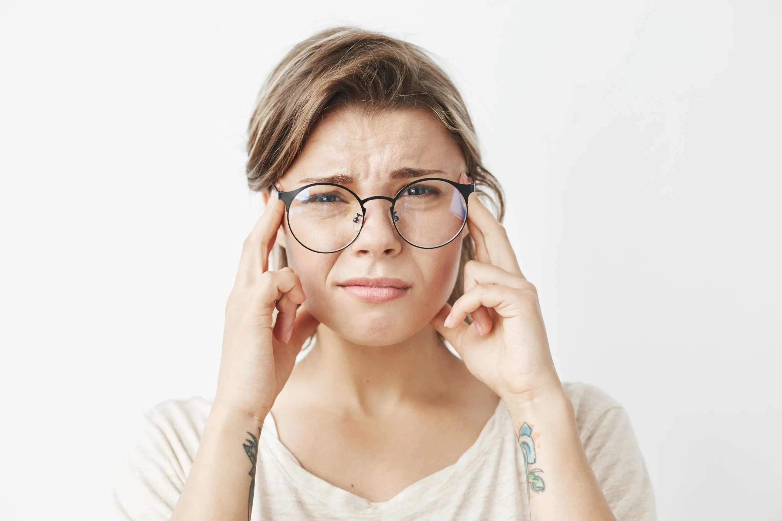 Blog young pretty girl in glasses thinking frowning looking at camera with fingers on temples over white background.